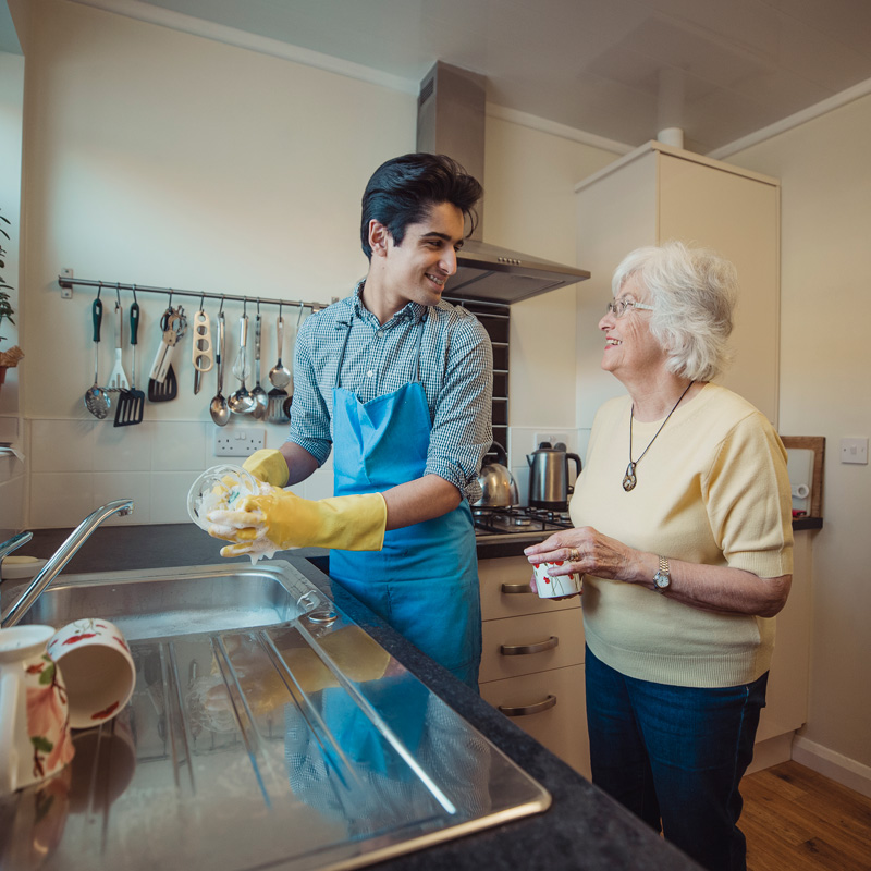 A boy is washing utensils for seniors in Phoenix, AZ