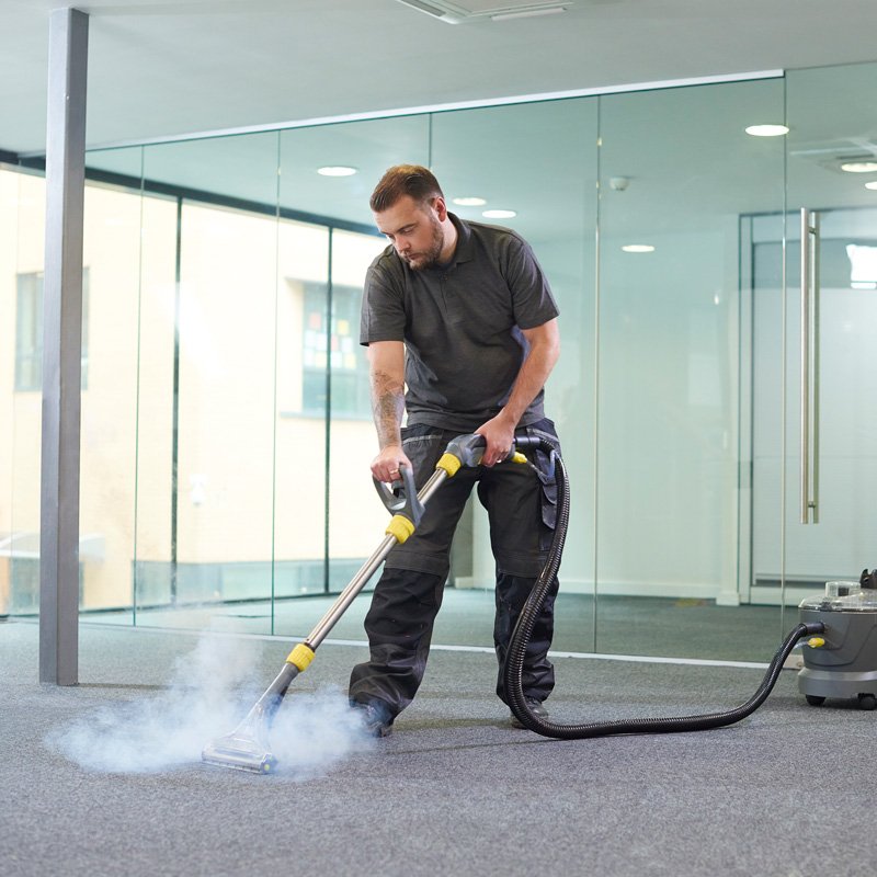 A man vacuuming a carpet, demonstrating cleaning services for commercial spaces in Phoenix, AZ.