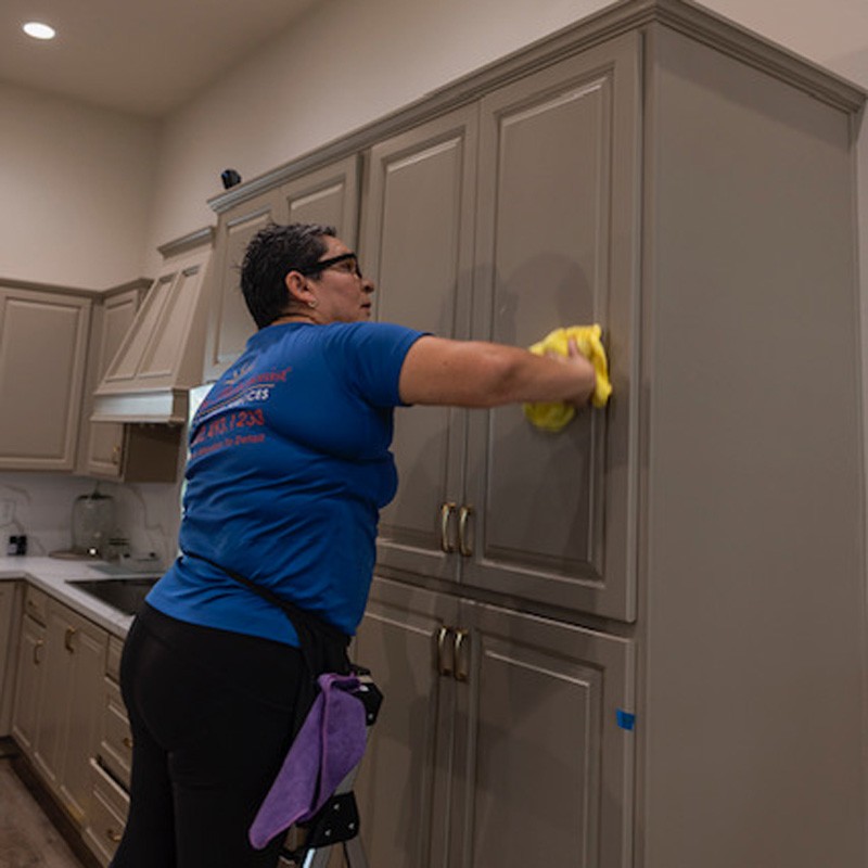 A woman scrubbing kitchen cabinets, showcasing a clean and organized space in Phoenix, AZ.