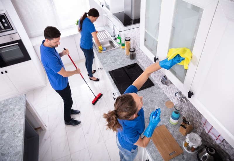 Three people mop a kitchen floor in Phoenix, AZ, as part of Move-In & Move-Out Cleaning services.