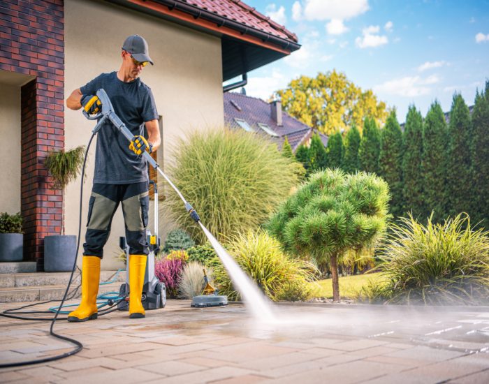 A man in a black shirt & boots cleans a patio, highlighting patio cleaning services in Phoenix, AZ.