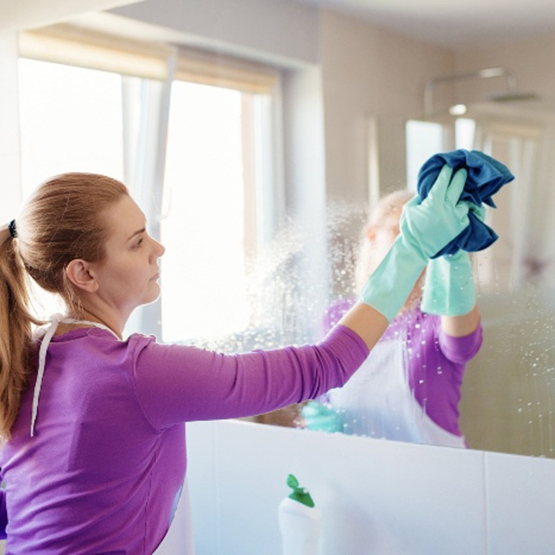 Woman sanitizing tiles and fixtures during bathroom cleaning in Phoenix, AZ
